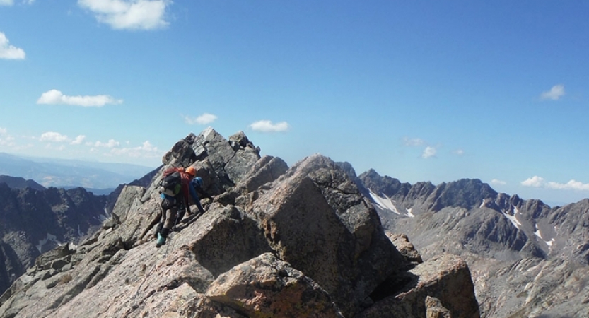 outward bound students wearing safety gear make their way along a high rocky ridge